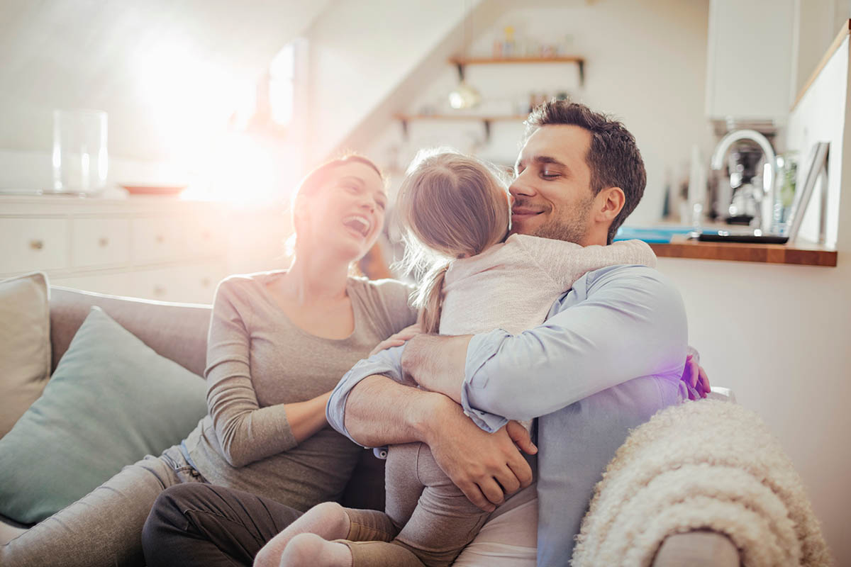 Happy young family relaxing on the couch at home hvacServices 2 1200x800 1
